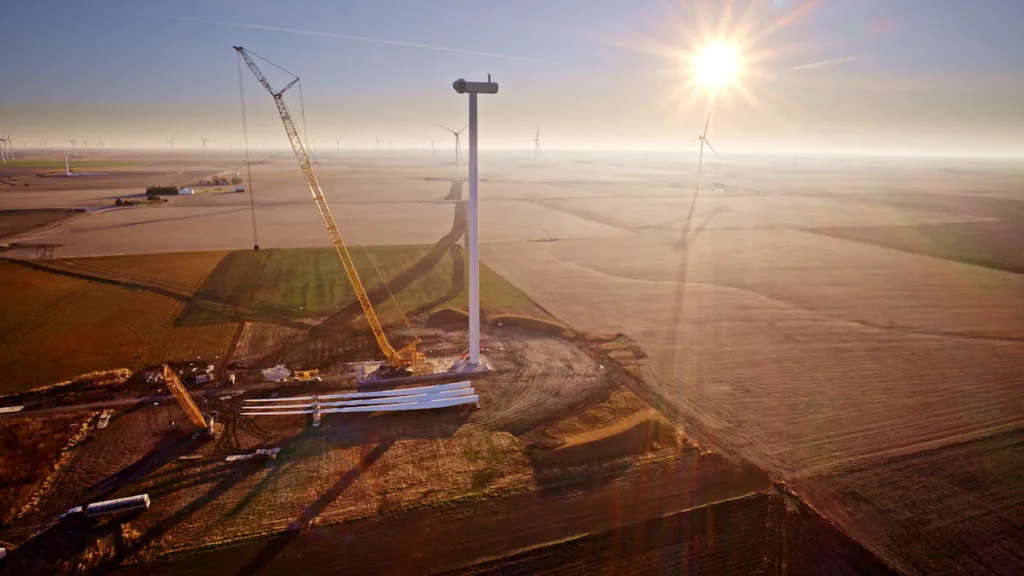 Aerial view of wind turbine construction site backlit in sun dusk